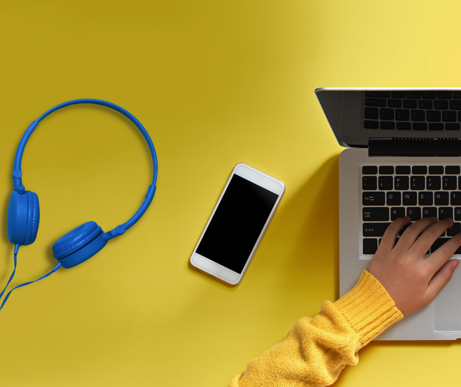 laptop, smartfon i niebieskie słuchawki na zółtym tle