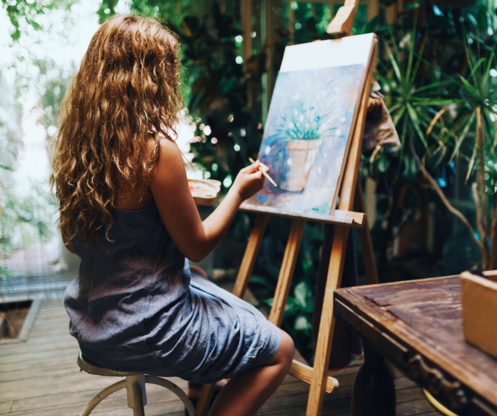 dziewczyna malująca obraz stojący na sztaludze